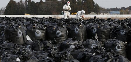Dekontaminierungsarbeiter mit Plastiksäcken voller radioaktiver ... Dekontaminierungsarbeiter mit Plastiksäcken voller radioaktiver ...
